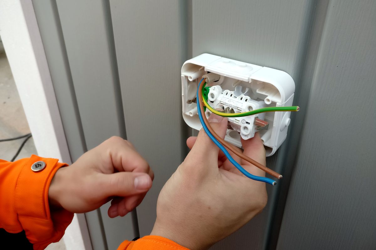 Een elektricien sluit de draden van een stopcontact aan