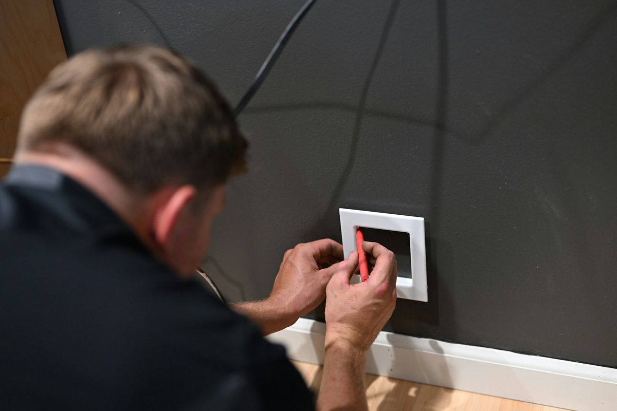 Een elektricien zet het raam van een schakelaar recht tegen de muur